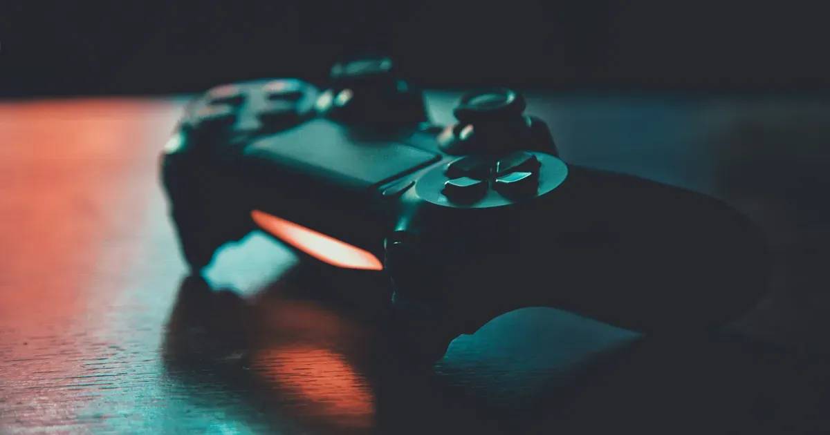 Manette de jeu vidéo éclairée dans la pénombre, métaphore du pilotage de l'informatique